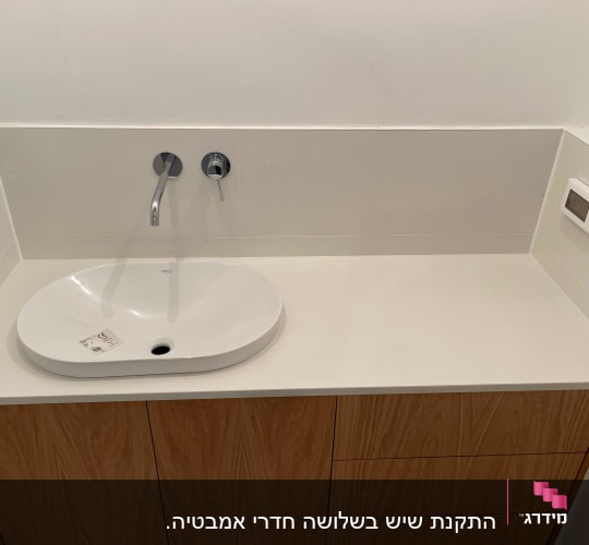 כיור מונח על משטח שיש לבן בחדר אמבטיה